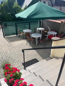 a patio with tables and chairs and a green umbrella at Tawerna Michałowscy in Mielno