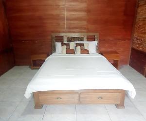 a bedroom with a large bed with white sheets and pillows at Tety's Wooden Villa in Labuan Bajo +12 photos