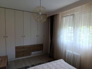 a bedroom with a chandelier and a bed and a window at Apartman Kokan in Obrenovac