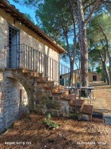 a stone building with a staircase next to a tree at La casa dei breton in Magione