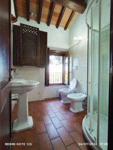 Un baño con dos inodoros, un lavabo y una ducha. en La casa dei breton, en Magione
