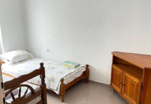 a small bedroom with a bed and a wooden dresser at Hostel Flash in Ulcinj