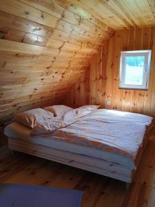 a bed in a log cabin with a window at Under Milky Way in Podgora