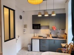 Una cocina con gabinetes azules y una encimera. en Studio à 100 m de la plage PIQUOT 44, en Granville 5 fotos más