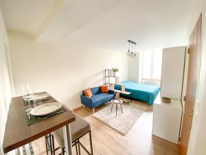a living room with a blue couch and a kitchen at Studio coeur de ville paisible in Alençon
