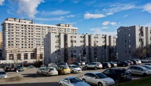 a parking lot with cars parked in front of buildings at Green Apartment! in Prishtinë