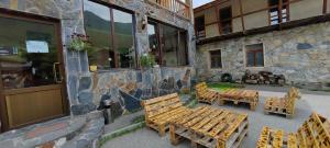 a group of wooden tables and chairs next to a building at Hotel Svanseti in Mestia