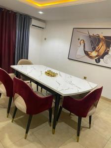 a white table with red chairs and a painting on the wall at HOME-AWAY APARTMENTs in Lagos