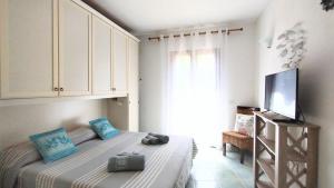 a bedroom with a bed with blue pillows and a television at Appartamento La Terrazza - Località Cala Gavetta in La Maddalena +64 photos