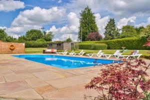 a swimming pool with two lawn chairs at Ashfield Place Farm by Group Retreats in Stowmarket