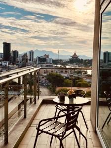 a table and chairs on a balcony with a view of a city at Kuching City Center Riverine Apartment With Balcony and Marvelous View in Kuching