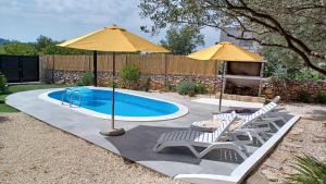 a pool with two chairs and an umbrella at M&S Paradise Bilice, Šibenik in Vrulje