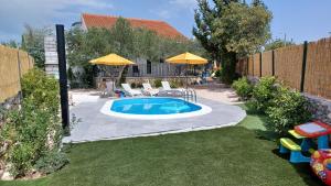 a small pool with chairs and umbrellas in a backyard at M&S Paradise Bilice, Šibenik in Vrulje +50 photos