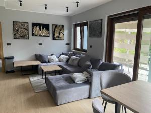 a living room with a gray couch and tables and a table at Arcadia Home in Będzin