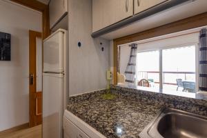 une cuisine avec un évier et un réfrigérateur dans l'établissement FABULOSO APARTAMENTO CON VISTAS AL MAR, à Playa de Gandia