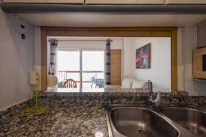 une cuisine avec un évier et une vue sur un salon dans l'établissement FABULOSO APARTAMENTO CON VISTAS AL MAR, à Playa de Gandia 14 autres photos
