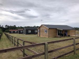 a row of houses in a field behind a fence at Nightingale Lodge - Adults Only in Lackford