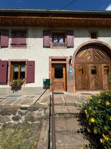 Una casa con puertas y ventanas de madera y flores. en GÎTE EMERAUDE, en Plaine