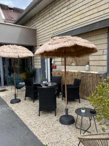 a patio with two umbrellas and chairs and tables at Hotel Best Western La Mare Ô Poissons in Ouistreham