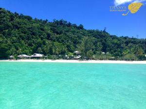 a beach with turquoise water and a mountain at Thanya Beach Resort - SHA Plus in Ko Ngai