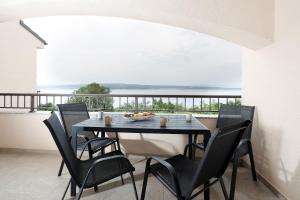 a dining room with a table and chairs and a balcony at Apartments Via Sole Dramalj in Dramalj