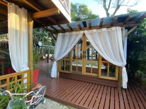 a wooden deck with awning and curtains on it at Chale Sobre Rodas Spa Exclusive - Localizado Próximo do Centro in Canela