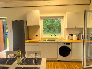 a kitchen with white cabinets and a sink and a dishwasher at Letnia Ostoja Wieprz nad Jeziorakiem in Zalewo