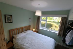 a bedroom with a bed and a window at Woodlands A Tranquil Retreat in Exbourne
