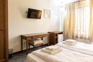 a hotel room with two beds and a desk and a television at Hotel Domenic FREE PARKING in Plovdiv
