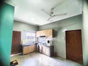 a kitchen with green walls and a ceiling fan at homestay juara meru setia alam klang in Kapar