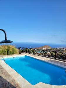 a blue swimming pool with the ocean in the background at Casa Rural Achacay in Fasnia