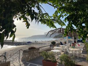 a beach with white tables and chairs and the ocean at Cozy Studio in Pisciotta