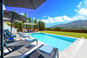 una piscina con sedie e un ombrellone di Luminosa Luxury Villa a Chania