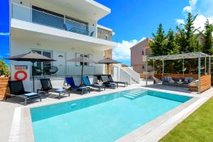 una casa con piscina con sedie e ombrelloni di Luminosa Luxury Villa a Chania