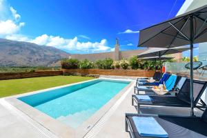 una piscina con sedie e un ombrellone di Luminosa Luxury Villa a Chania