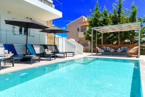 una piscina con sedie e ombrelloni accanto a una casa di Luminosa Luxury Villa a Chania