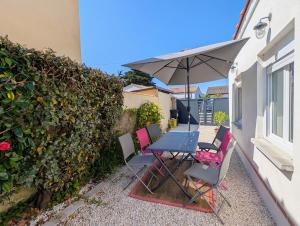 a table and chairs with an umbrella on a patio at Maison cozy proche des plages - Animaux acceptés ! in La Bernerie-en-Retz