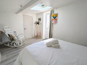 a bedroom with a white bed and a chair at Maison cozy proche des plages - Animaux acceptés ! in La Bernerie-en-Retz