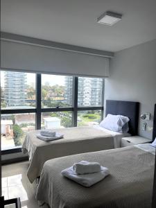 two beds in a room with a large window at ONIX BY GM RENTALS in Punta del Este +31 photos