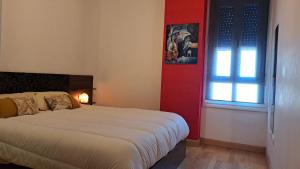 1 dormitorio con cama blanca y puerta roja en La Casa de Sira - A 5 min de la playa a pie - Parking incluido, en Luanco
