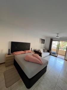 une chambre avec un lit avec des oreillers roses dessus dans l'établissement Jolana apartment Los Cristianos, à Los Cristianos