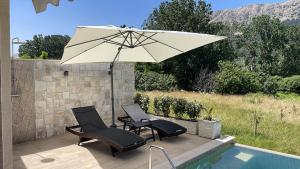 a patio with two chairs and an umbrella next to a pool at Villa Dupini in Baška