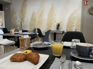 a table with a plate of bread and orange juice at Hotel Best Western La Mare Ô Poissons in Ouistreham