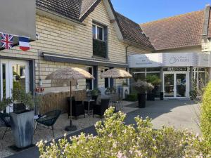 a group of chairs and umbrellas in front of a building at Hotel Best Western La Mare Ô Poissons in Ouistreham