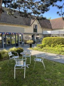 a group of chairs and a table in the grass at Hotel Best Western La Mare &Ocirc; Poissons in Ouistreham
