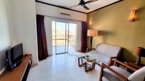 a living room with a couch and a tv at Gold Coast Morib Apartment in Banting