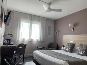 a bedroom with a bed and a desk and a window at Cit'Hotel Le Ch&ecirc;ne Vert in Les Sables-dʼOlonne