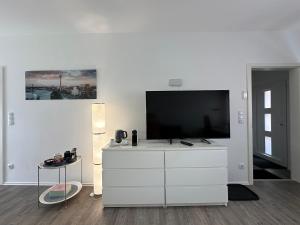 a living room with a tv on a white dresser at Auszeit Apartment Düsseldorf in Düsseldorf