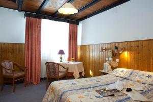 a hotel room with a bed and a table and chairs at Logis Hôtel La Petite Chaumière in Gex