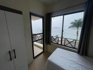 a bedroom with a bed and a large window at Casa 3 qtos beira mar praia exclusiva e piscina in Angra dos Reis